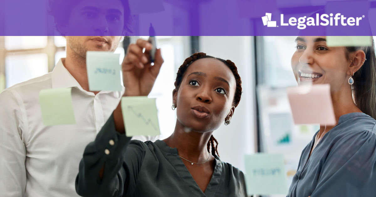 Three colleagues collaborating in an office, brainstorming ideas using sticky notes on a glass wall. A woman in the center is writing on the glass while the others observe and discuss. The LegalSifter logo appears at the top with a purple banner.