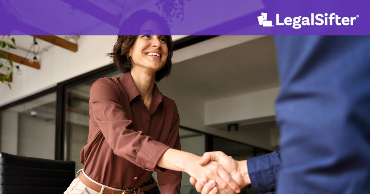 A smiling professional shaking hands with a colleague in a modern office, symbolizing a successful agreement and smooth contract renewal process