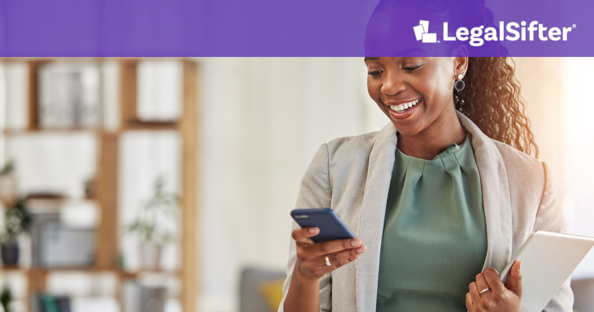 A smiling professional woman stands in a bright office holding a smartphone and a tablet, looking at her phone with a cheerful expression. A purple banner with the LegalSifter logo appears at the top of the image.